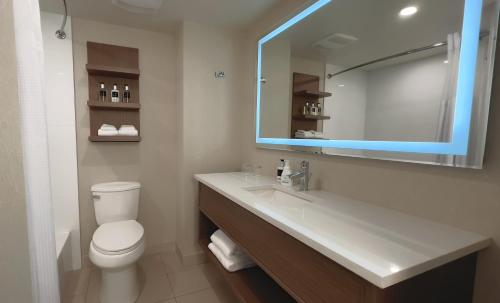 a bathroom with a toilet and a sink with a mirror at Coast Capri Hotel in Kelowna