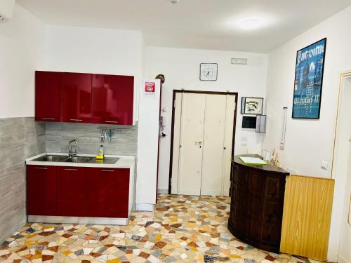 a kitchen with red cabinets and a sink and a counter at Le Maschere in Mestre