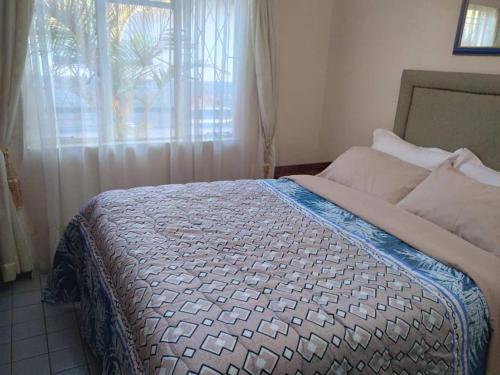 a bedroom with a large bed with a window at Cottage - Sleeps 4 Pool & Private Parking in Harare