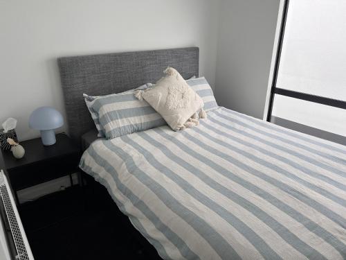 a bed with a blue and white striped sheets and a pillow at Stylish 2 bedrooms townhouse in central Wellington in Wellington