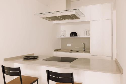 una cucina bianca con lavandino e due sedie di City Stays São Lázaro Apartments a Lisbona