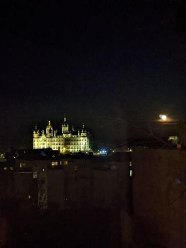 a large white building with lights on it at night at Schlosskönig - Modernes & zentrales Apartment mit Balkon und Arbeitsplatz in Schwerin
