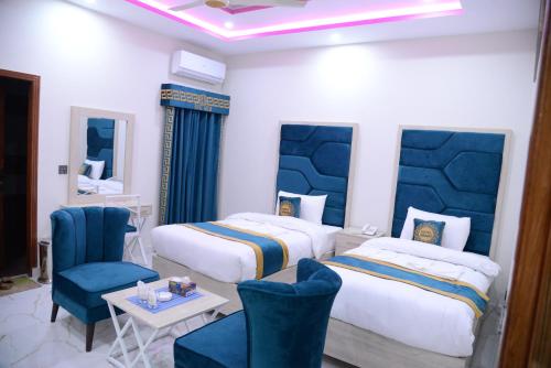 a hotel room with two beds and a table and chairs at Hotel Grand Lahore in Lahore