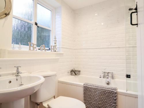 a white bathroom with a toilet and a sink at 4 East Green, Southwold in Southwold