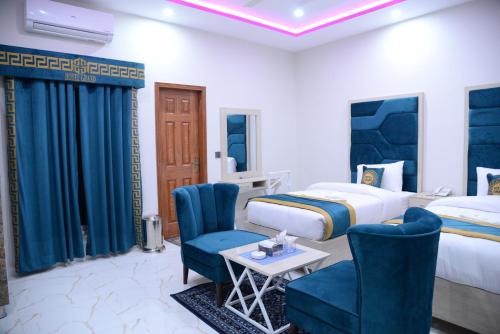 a hotel room with two beds and blue chairs at Hotel Grand Lahore in Lahore