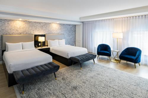a hotel room with two beds and two chairs at Halifax Tower Hotel & Conference Centre, an Ascend Collection Hotel in Halifax