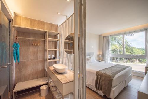 a bedroom with a bed and a bathroom with a window at Pousada Paraíso Noronha in Fernando de Noronha