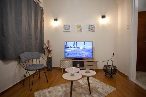 a living room with a tv and two chairs and a table at Lovely Nest Piraeus in Piraeus