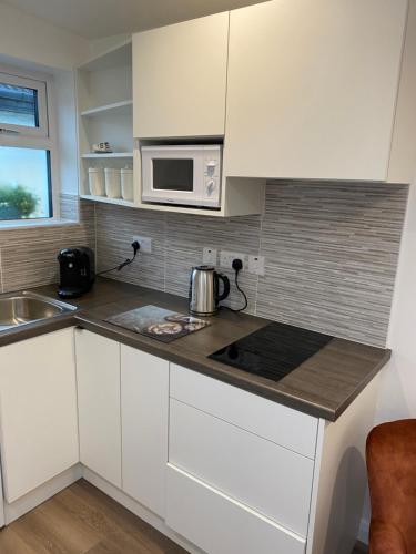 a kitchen with white cabinets and a microwave at Lavender Mews in Tuam