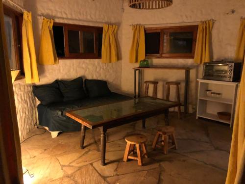 Sala de estar con sofá, mesa y taburetes en Hermosa Cabaña a 2 Cuadras De Los Botes, La Paloma, en La Paloma