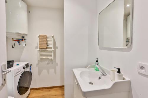Un baño blanco con lavabo y lavadora. en L'iris #Netflix #Centre-ville, en Cognac