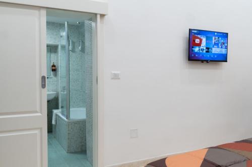 a bathroom with a tv on the wall next to a bed at Olina residence in Naples