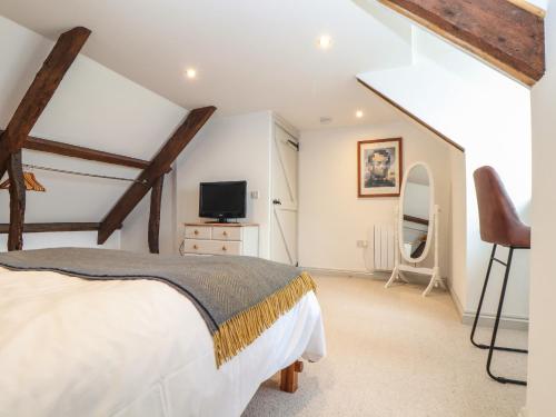 Un dormitorio con una cama y un televisor de pantalla plana. en Ty Bryn, en Marazion