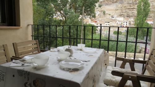 una mesa blanca con tazones y platos en el balcón en Casa Rural Pepe el Tranquilo, en Alcalá del Júcar