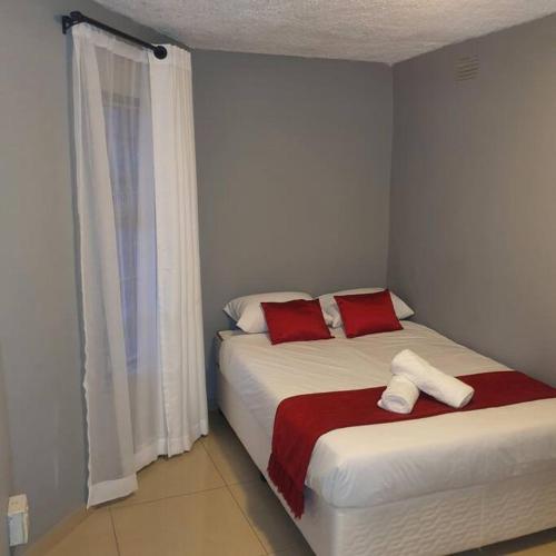 a bedroom with a bed with red and white pillows at Imanna 111 in Durban