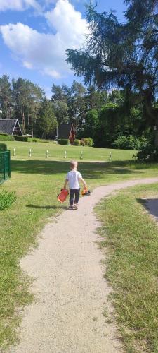 a little boy holding two kites on a dirt road at Ferienhaus-Zum-Eichkater-am-Duemmer-See in Marienthal