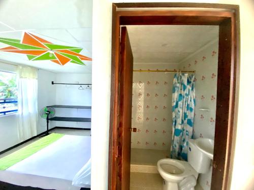 2 fotos de un baño con aseo y un dormitorio en La Morena Hospedaje, en Acacías