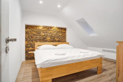 Bett in einem Zimmer mit einer Steinmauer in der Unterkunft Apartmán Kryštof - Jáchymov in Jáchymov