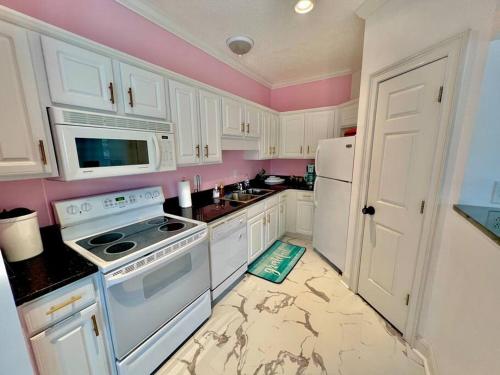 a kitchen with white appliances and pink walls at Lovely Home Near Myrtle Beach in Myrtle Beach
