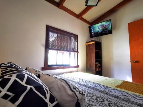 a bedroom with a bed and a flat screen tv at Kimün Rise Cabaña Céntrica Villarrica in Villarrica