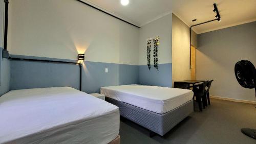 Cette chambre comprend deux lits et une table avec une chaise. dans l'établissement Suíte n° 07 - Praia das Pitangueiras, à Guarujá