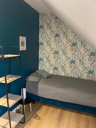 - une petite chambre avec un lit et un mur bleu dans l'établissement Gîtes 6A et 6B, à Bailleul-Sir-Berthoult