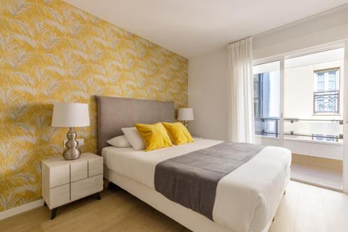 een slaapkamer met een groot bed met gele kussens bij Spacious & Quiet apartment by HelloMalaga - AZAHAR in Málaga