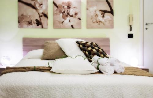 1 cama con almohadas blancas y cuadros en la pared en La Chiostrina, en Roma