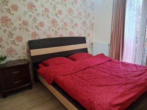 a bedroom with a bed with a red comforter at Saburtalo in Tbilisi City