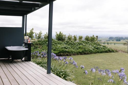 a bath tub on a deck with purple flowers at Birds Eye View in Havelock North