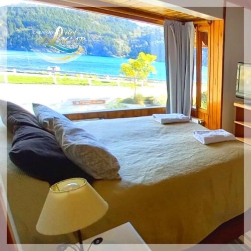 a bedroom with a large window with a view of a beach at Cabañas Del Lacar in San Martín de los Andes