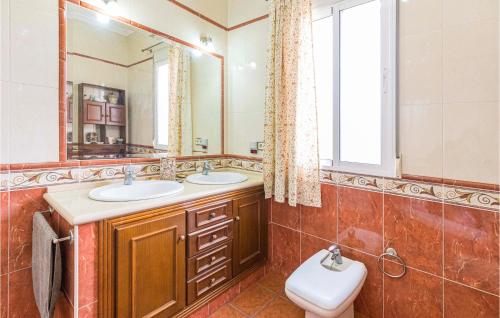 a bathroom with two sinks and a toilet and a mirror at Gorgeous Home In Arahal With Kitchen in El Arahal