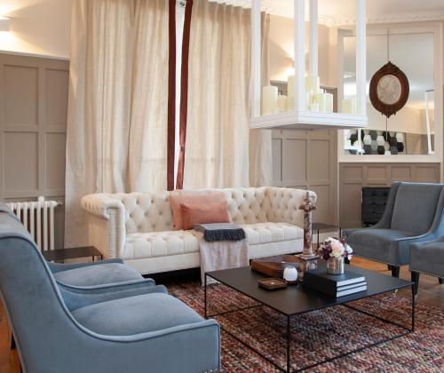 a living room with a white couch and two blue chairs at L’orée du bois des rois in Ury