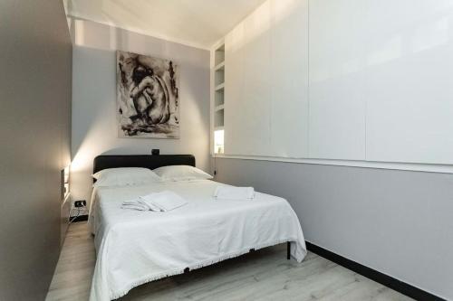 Genova Garden, vicino al Gaslini e Boccadasse في جينوا: غرفة نوم بسرير ابيض مع لوحة على الحائط