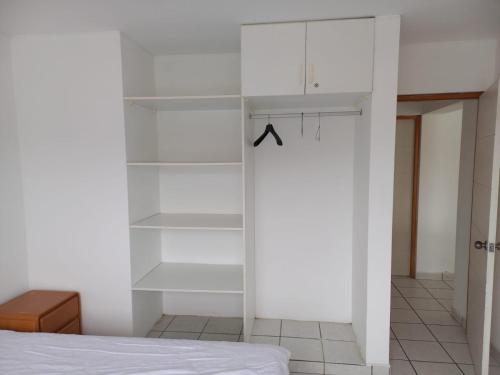 a bedroom with white shelves and a bed at Departamento super cómodo Playa Naplo in Naplo