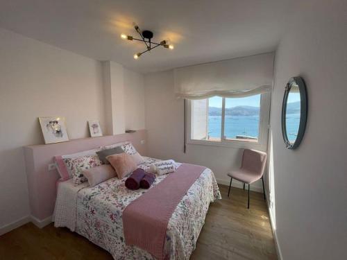 um quarto com uma cama com uma janela e uma cadeira em Covelodge - Piso a pocos metros de la playa em Pontevedra