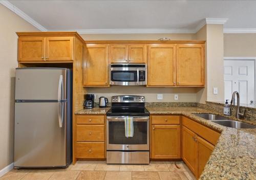 a kitchen with wooden cabinets and stainless steel appliances at The Dawn on Galveston Beach in Galveston