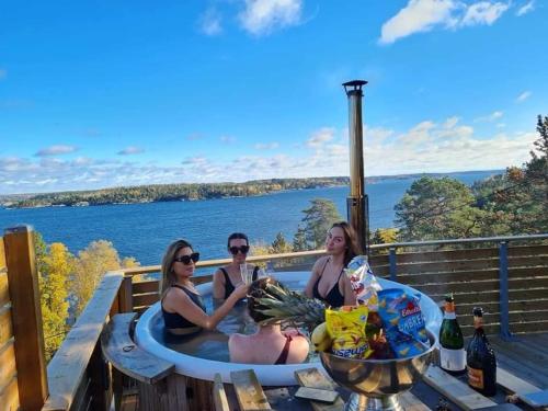 tres mujeres sentadas en un jacuzzi en una terraza en Nils Bastu Spa och Övernattningstuga en Tyresö