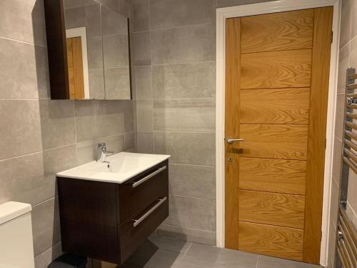 a bathroom with a sink and a wooden door at Fantastic Large 2 X Bedroom Flat, Free Parking in Sale