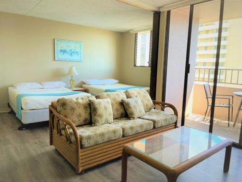 een woonkamer met een bank en een bed bij Royal Kuhio 1710 - Spacious Studio with Stunning Ocean City Views in the Heart of Waikiki! in Honolulu