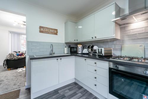 a kitchen with white cabinets and a stove at Nhyira Private Parking CHic Three Bedrooms Garage 2 Shower rooms Classy Home in Hull