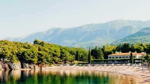 a body of water with chairs and mountains in the background at Varja 3 Apartment in Pržno