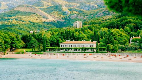 a beach with chairs and a building and mountains at Varja 3 Apartment in Pržno