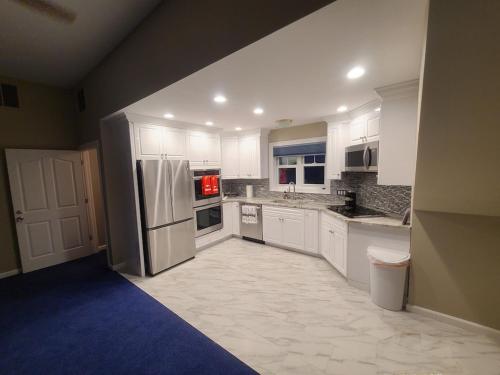a kitchen with white cabinets and a stainless steel refrigerator at Large Waterfront Modern Beach House in East Haven