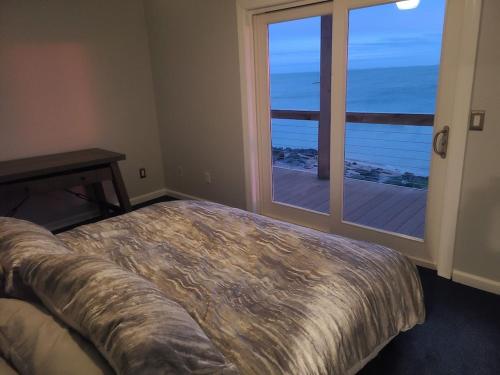 1 dormitorio con cama y ventana grande en Large Waterfront Modern Beach House, en East Haven