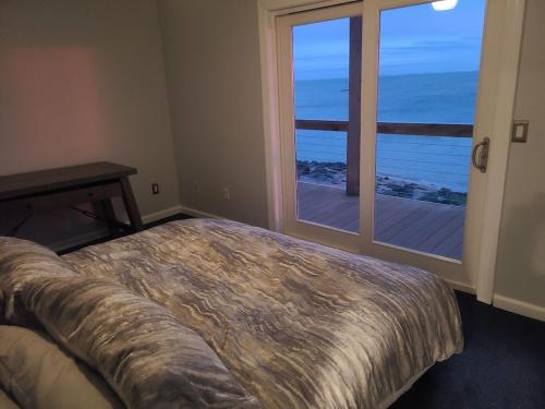 a bedroom with a bed and a large window at Large Waterfront Modern Beach House in East Haven