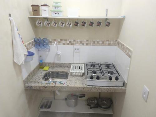 a small kitchen with a stove and a sink at Cantinho da Gigi in Peruíbe