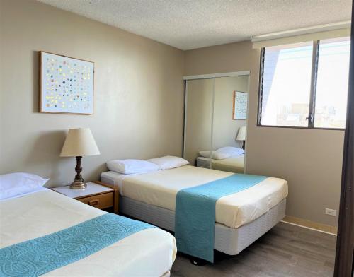 a hotel room with two beds and a mirror at Royal Kuhio 2309 - Spacious Studio with Stunning Ocean Views in the Heart of Waikiki! in Honolulu