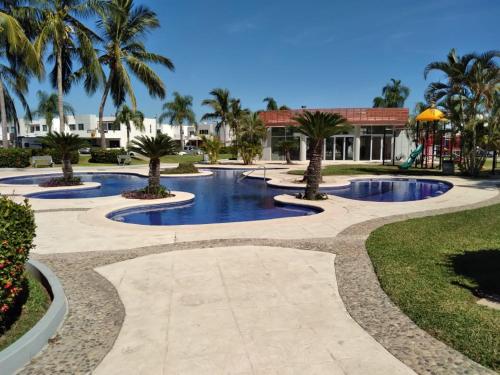 a resort pool with palm trees and a playground at CASA CERRITOS MAZATLAN in Mazatlán