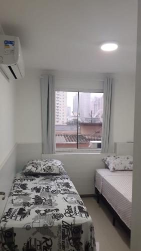 a small bedroom with a bed and a window at Apto temporada Itapema sc in Itapema